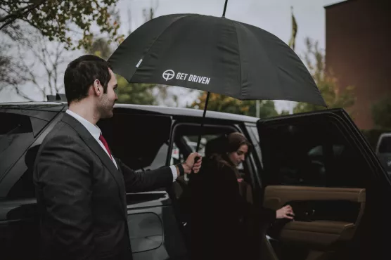 private driver holding umbrella for customer
